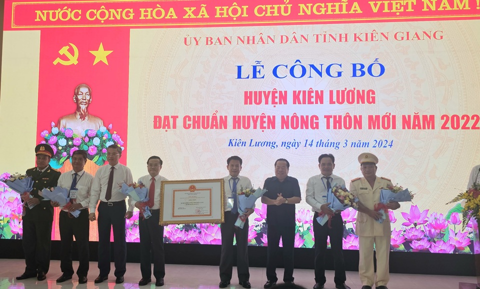 Ông Mai Văn Huỳnh - Phó Bí thư Thường trực Tỉnh ủy Kiên Giang (thứ 3 từ phải sang) và ông Nguyễn Lưu Trung - Phó Chủ tịch UBND tỉnh Kiên Giang (thứ 3 từ trái sang) trao quyết định của Thủ tướng và tặng hoa cho lãnh đạo Huyện ủy, UBND huyện Kiên Lương. (Ảnh Hữu Tuấn)