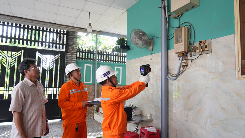 Anh Trần Thanh Tuấn (cầm máy camera đo nhiệt) và anh Tạ Minh Đờn - Công ty Điện lực Bình Chánh kiểm tra điện tại điểm bầu cử ấp 12, xã Bình Hưng. Ảnh: Minh Khuê.